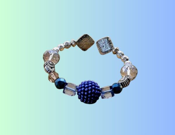 Pulsera Artesanal con Cuentas Cristalinas – Azul y Plateado Pulsera elástica hecha a mano con cuentas transparentes tipo cristal, detalles metálicos en plateado y un llamativo centro azul texturizado. Combina elegancia y estilo moderno, ideal para uso diario o como accesorio distintivo en ocasiones especiales. Ligera, cómoda y única. Perfecta para regalar o complementar cualquier outfit.